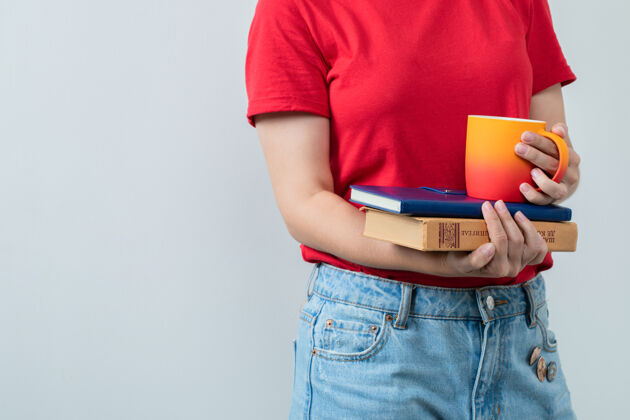 人类穿着红衬衫的年轻女孩手里拿着书和一杯饮料姿势茶员工