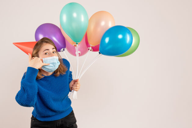 情感正面图戴面具的年轻女性手持五颜六色的气球病毒乐趣面具