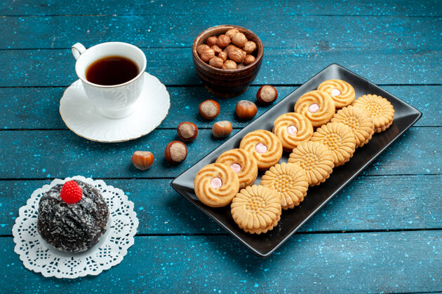 饼干一杯茶 配坚果和饼干 放在乡村蓝桌上 糖饼干 甜饼干蛋糕杯子蛋糕食物