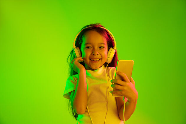 脸美丽的女性半身像 隔离在霓虹灯下的绿色背景上年轻感性的女孩人类情感 面部表情概念使用智能手机进行虚拟博客 自拍 聊天 游戏青少年情感成功