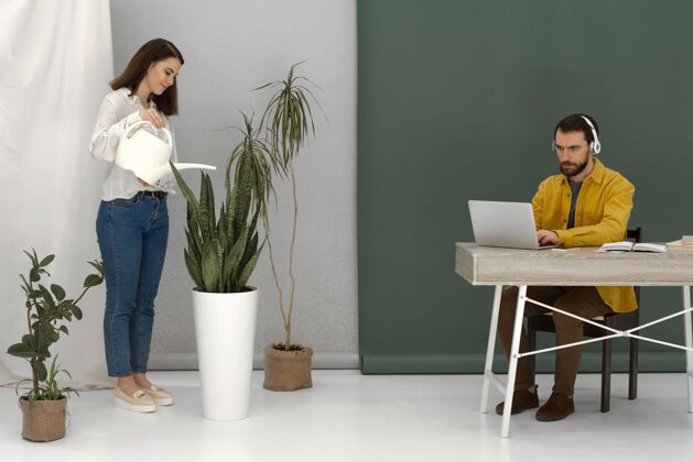 男性女人在给植物浇水 男人在用笔记本电脑女人排毒科技