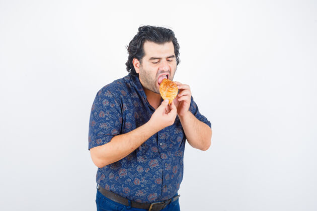 产品成熟的男人吃糕点产品在衬衫和饥饿的样子 前视图冷餐厅冷却器