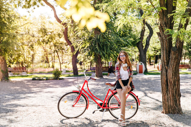 休闲漂亮苗条的女孩坐在红色的自行车上快乐时尚的女人享受活跃的周末周末夏天骑手
