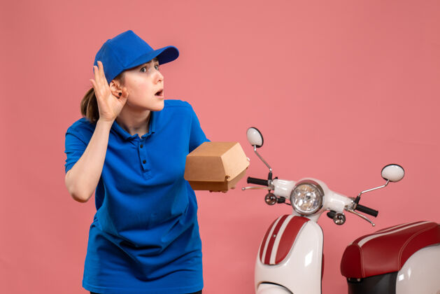 小正面图带着小食品包的女快递员听着粉色的工作服送货工工作自行车工披萨女包装球员粉色