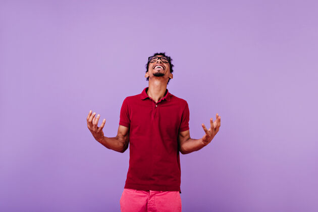 紫色好幽默的男模特穿着红色t恤抬头看乐观的非洲年轻人玩得开心快乐成人人