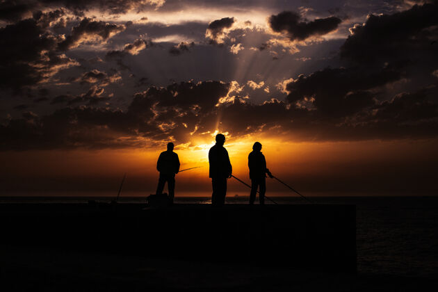 旅行夕阳下海滩上渔夫的剪影街道夏天城市