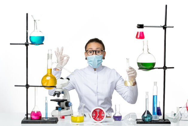 科学前视图：身着白色医疗服的女化学家 白色背景上有面罩 化学家实验室病毒冠状病毒飞溅解决方案医学飞溅
