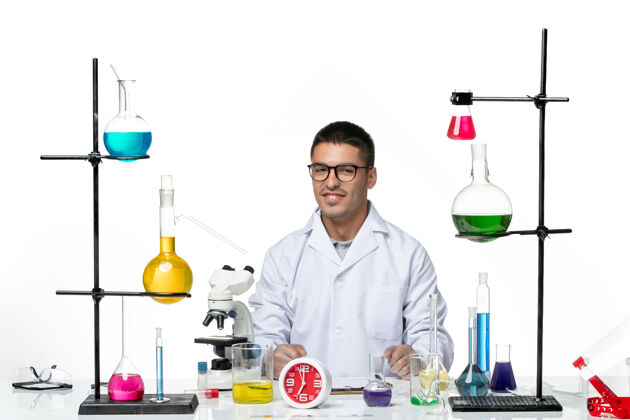 大流行前视图穿着白色医疗服的男性化学家坐在白色背景病毒科学柯维德大流行实验室的解决方案坐科学实验室