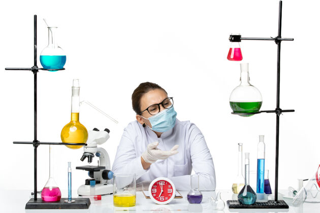 面罩前视图穿着医疗服的女化学家戴着面罩坐在白色背景上的溶液飞溅实验室病毒化学冠状病毒视图科学病毒