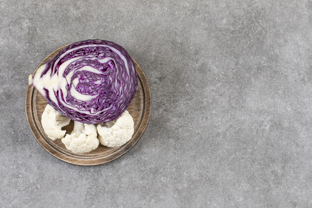 有机石桌上放着一盘紫色卷心菜和花椰菜蔬菜切健康