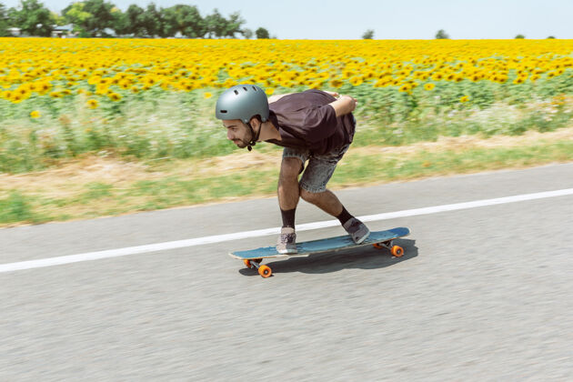 滑板在阳光明媚的日子里 滑板运动员在城市的街道上玩花样年轻人骑着器械 玩着长板休闲活动 运动 极限 爱好和运动的概念和汽车一样快速度公园运动员