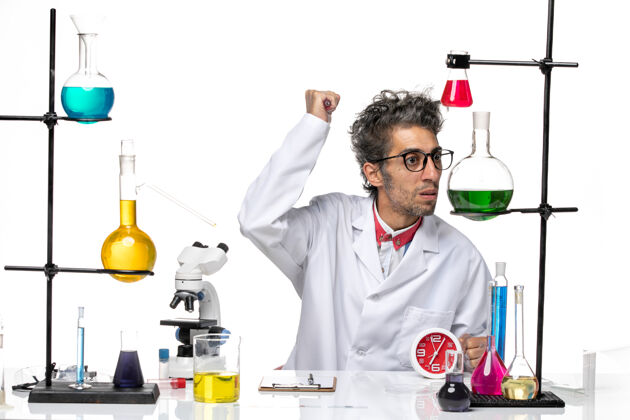 视图前视图穿着医疗服的男科学家坐在桌子前 用白色背景上的解决方案研究科维德实验室病毒健康化学坐医疗外套