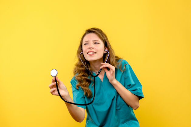 女医生黄色墙上女医生使用听诊器的正面图保健仪器成人