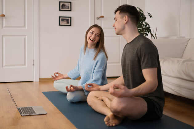 一起一对美丽的情侣在家一起练习瑜伽 用笔记本电脑上瑜伽课健康观看视频