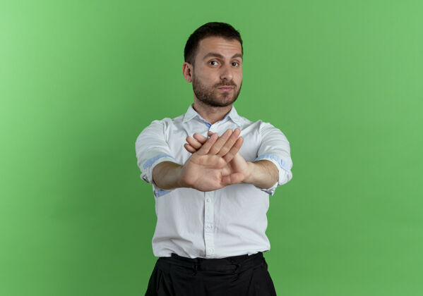英俊自信的帅哥双手交叉 在绿色的墙上做着不孤立的手势绿色自信手