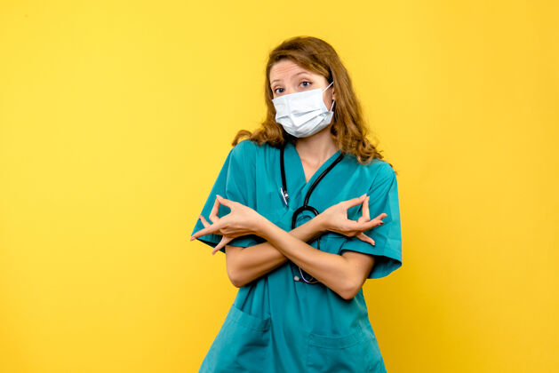 快乐黄色地板上戴着面罩的女医生的正面图情感医院的健康医生黄色女人职业