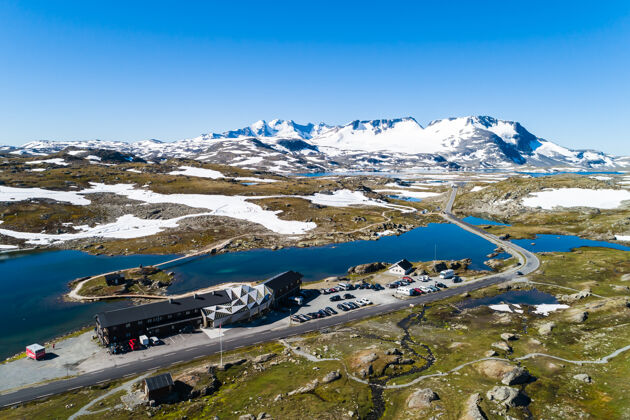 白天鸟瞰湖边滑雪中心周围崎岖的山脉景观在挪威湖边鸟瞰冬天