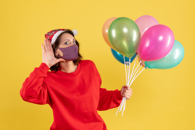 聚会正面图年轻女性手持气球 戴着黄色的无菌面具视图快乐氧气