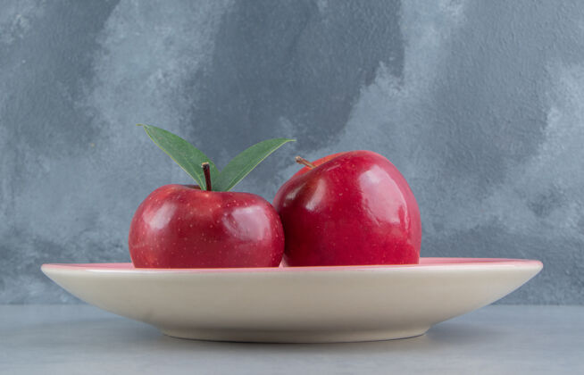 苹果大理石上有两个苹果的盘子拼盘风味新鲜