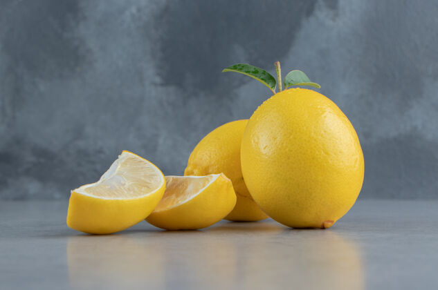 美味整个柠檬和切片展示在大理石上风味新鲜美味