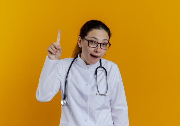 医学印象深刻的年轻女医生穿着医用长袍和听诊器戴着眼镜点了起来橙色眼镜穿
