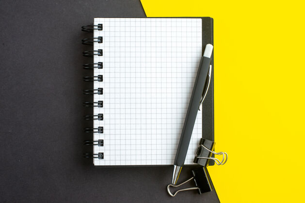 螺旋笔记本特写镜头螺旋笔记本上的书和笔在黑黄色的背景与自由空间活页夹保护套笔