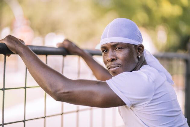 物理一个穿着白衬衫的非洲裔美国男性在公园里摆姿势的特写镜头男人健美强壮