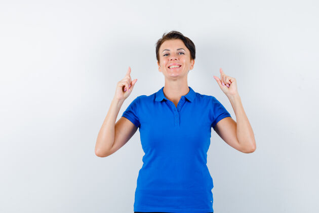 T恤成熟的女人指着蓝色t恤 看起来很自信正面视图指尖柔软提举