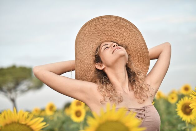 肖像微笑着戴着帽子的年轻女子在向日葵地里——幸福的概念自然白色成人