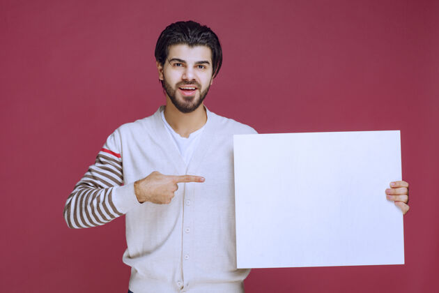 年轻一个男人拿着一块空白的创意板 指着它想引起注意员工人成人