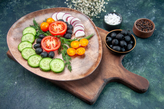 花侧视图新鲜切碎的蔬菜在棕色盘子上的木制砧板橄榄在碗盐大蒜素花上的混合色背景大蒜食物蔬菜
