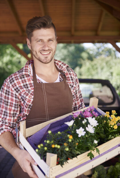 种植特写镜头：男人拿着装满五颜六色花朵的胸脯板条箱农场帅哥
