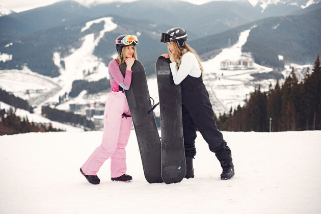 冷穿着滑雪板套装的女人在山上的运动员手拿滑雪板在地平线上关于运动的概念粉红色下雪板