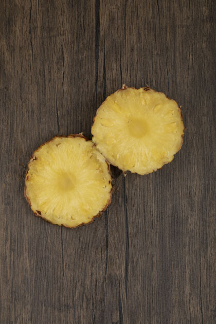 切割两片新鲜成熟的菠萝片放在木桌上美味俯视图整个