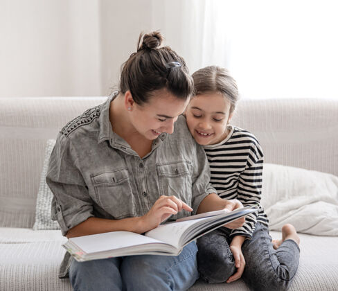 家庭作业开朗的妈妈和女儿在家休息 一起看书家庭休闲信息