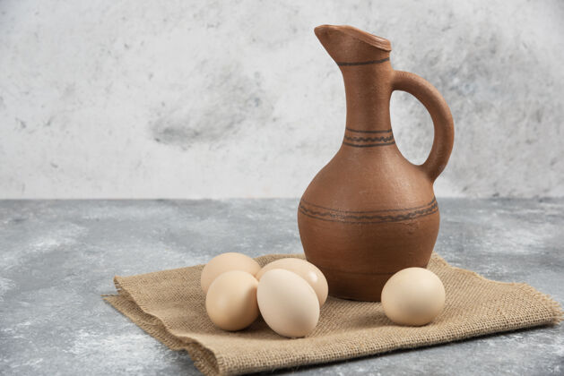 生的新鲜生鸡蛋和大理石表面的古董瓶瓶子鸡蛋烹饪