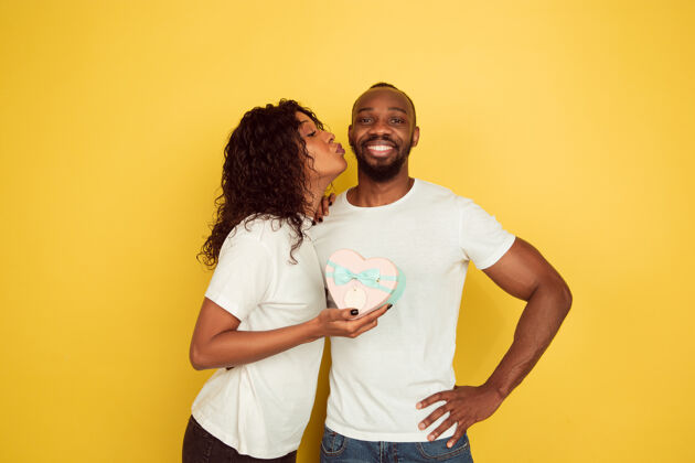 面部收到礼物很高兴情人节庆祝 快乐的非洲裔美国夫妇隔离在黄色工作室背景人类情感的概念 面部表情 爱情 关系 浪漫的节日人类立场民族