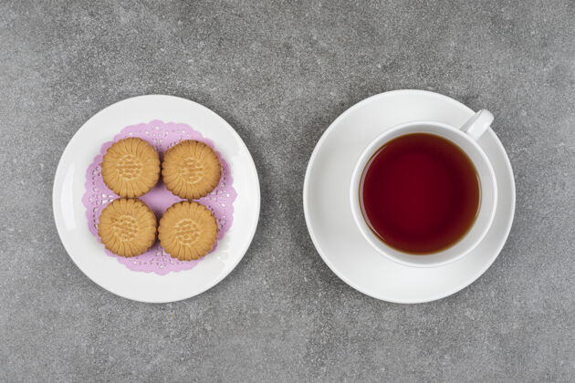 脆美味的圆形饼干和一杯茶放在大理石表面美味甜点杯