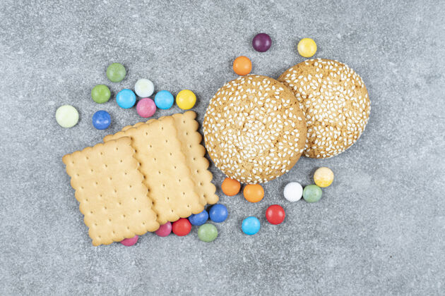 小吃饼干和五颜六色的糖果放在大理石表面美味芝麻餐