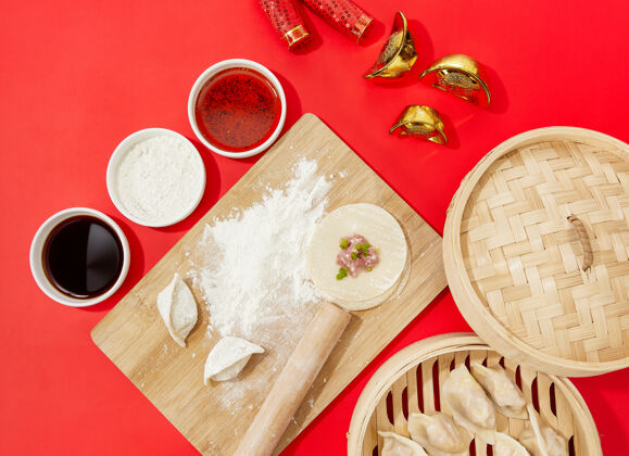 饮食上图特写的生饺子是在一个切菜板与面粉在红色的背景传统食物生的