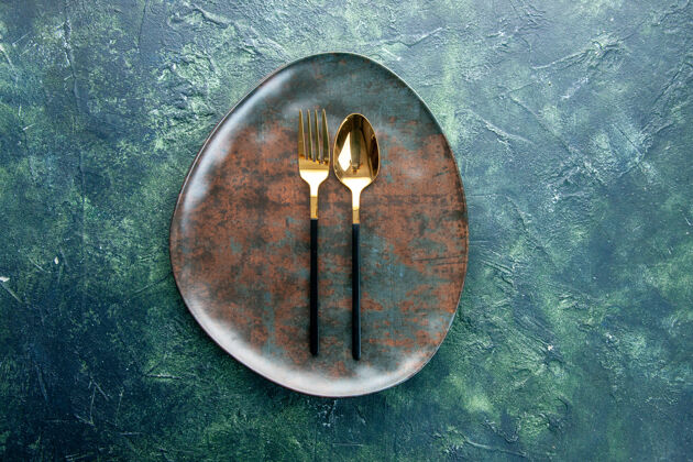 餐具俯视图黑色背景上的棕色空盘子和金色勺子餐厅食物厨房用餐餐具晚餐餐厅熨斗背景