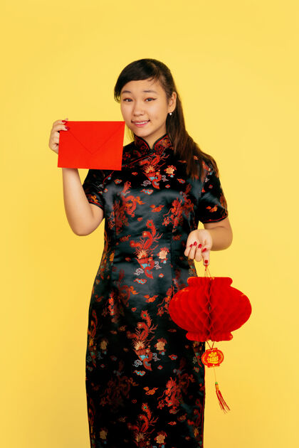 亚洲带着灯笼和信封微笑2020年中国新年快乐黄色背景上的亚洲少女肖像穿着传统服装的女模特看起来很快乐庆祝 情感复制空间服装季节美丽