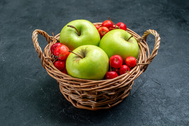 新鲜前视篮上有水果苹果和甜樱桃 深色表面上有水果浆果组成的新鲜树可食用的水果浆果视野