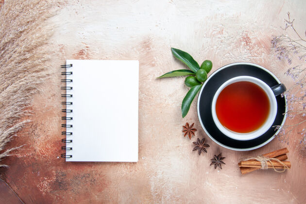 特写顶部特写查看一杯茶一杯茶肉桂棒柑橘类水果白色笔记本水果茶茶杯