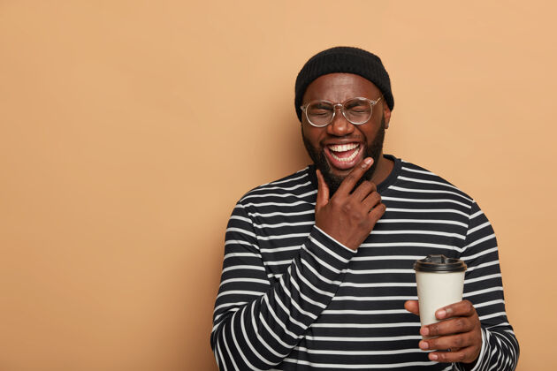 欢乐人 生活方式 情感观念快乐的黑人男子托着下巴 真诚地微笑 喝着外卖咖啡眼镜空白业余时间