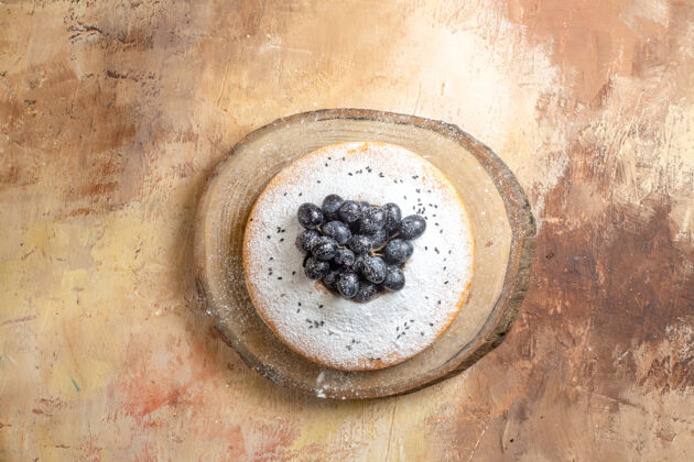 食物蛋糕俯视图切菜板上有黑葡萄和糖粉的蛋糕香草顶部葡萄