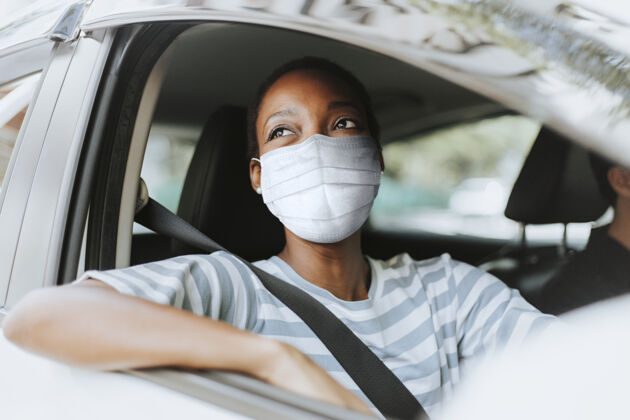 人们的照片戴着面具的女人开车经过冠状病毒大流行司机汽车