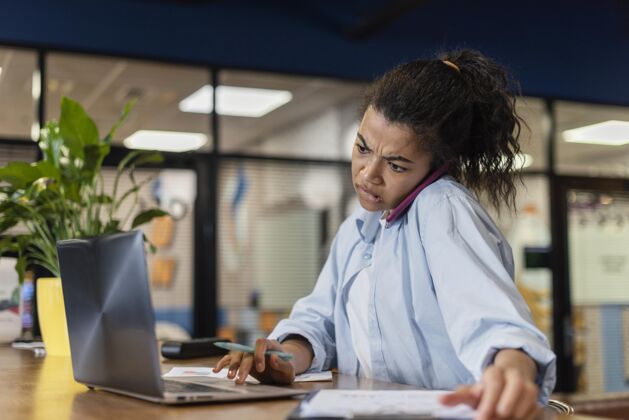 会议办公室里压力很大的女人用笔记本电脑和智能手机聊天压力横向雇员