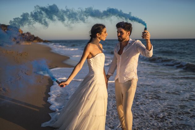 悬崖一对美丽的情侣在海滩上与蓝色烟雾弹合影的照片天空女人岛屿
