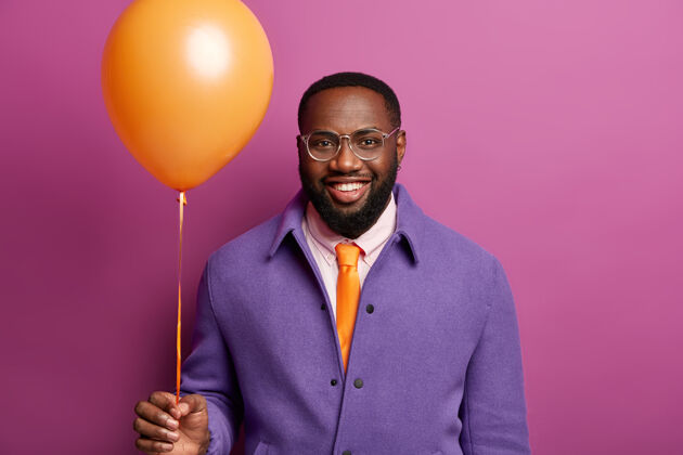 充气快乐男人的画像出现在雄鹿派对上 站在橙色的气球旁 笑容灿烂 喜气洋洋 祝贺朋友气球节日非洲